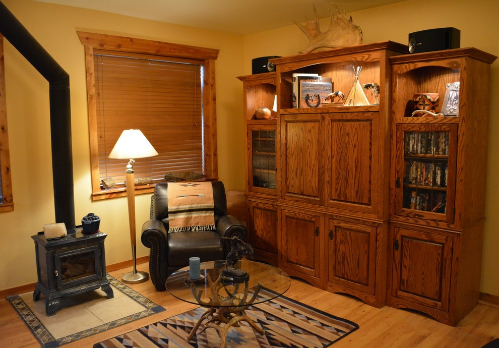 Foto de sala de estar cerrada de estilo americano de tamaño medio con paredes amarillas, suelo laminado, estufa de leña, marco de chimenea de yeso y televisor independiente
