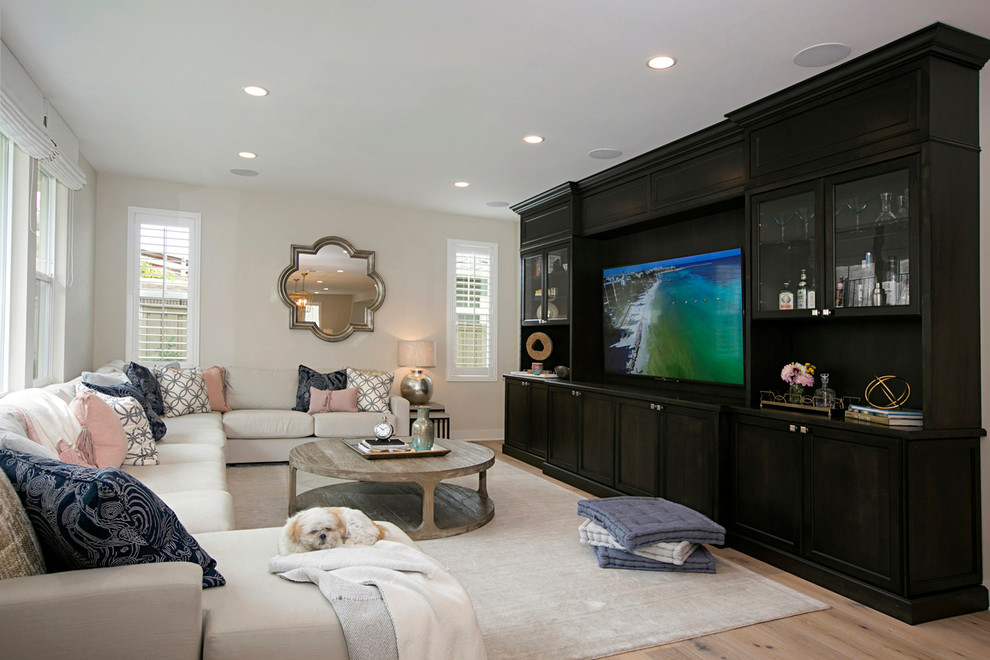 Example of a large transitional enclosed light wood floor and beige floor family room design in San Diego with beige walls, no fireplace and a media wall