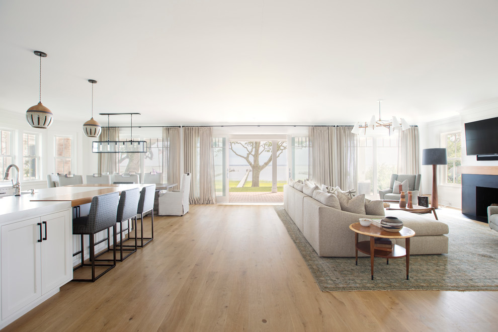 Cette image montre une salle de séjour design ouverte avec un mur blanc, parquet clair et une cheminée standard.