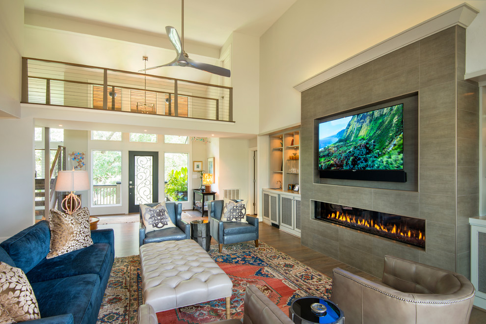 Großes, Offenes Stilmix Wohnzimmer mit TV-Wand, beiger Wandfarbe, braunem Holzboden, Gaskamin, gefliester Kaminumrandung und braunem Boden in Charleston