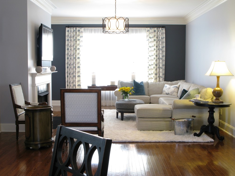 На фото: открытая гостиная комната среднего размера в стиле неоклассика (современная классика) с синими стенами, паркетным полом среднего тона, стандартным камином, фасадом камина из дерева и телевизором на стене