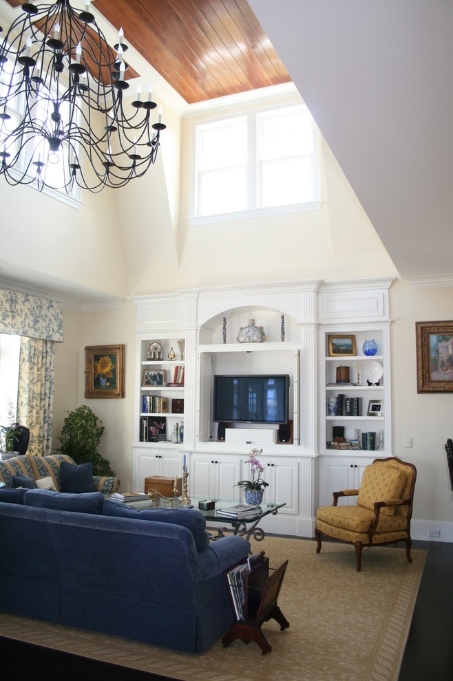 Ejemplo de sala de estar tipo loft tradicional de tamaño medio con paredes beige, suelo de madera oscura y pared multimedia