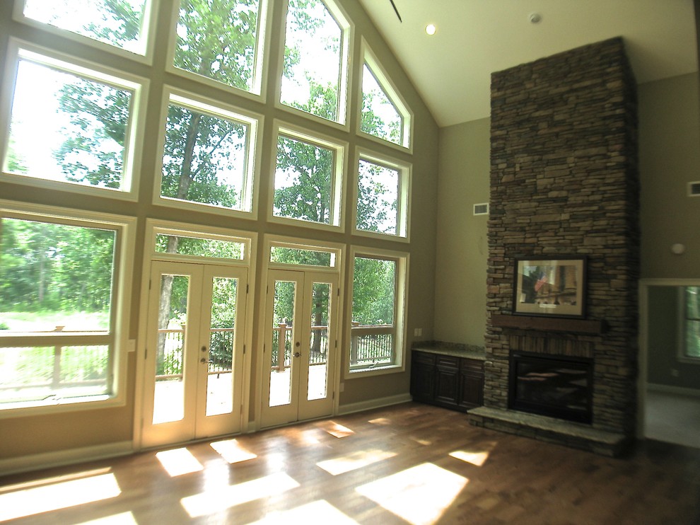 Exemple d'une salle de séjour craftsman avec un mur vert, un sol en bois brun, une cheminée standard et un manteau de cheminée en pierre.