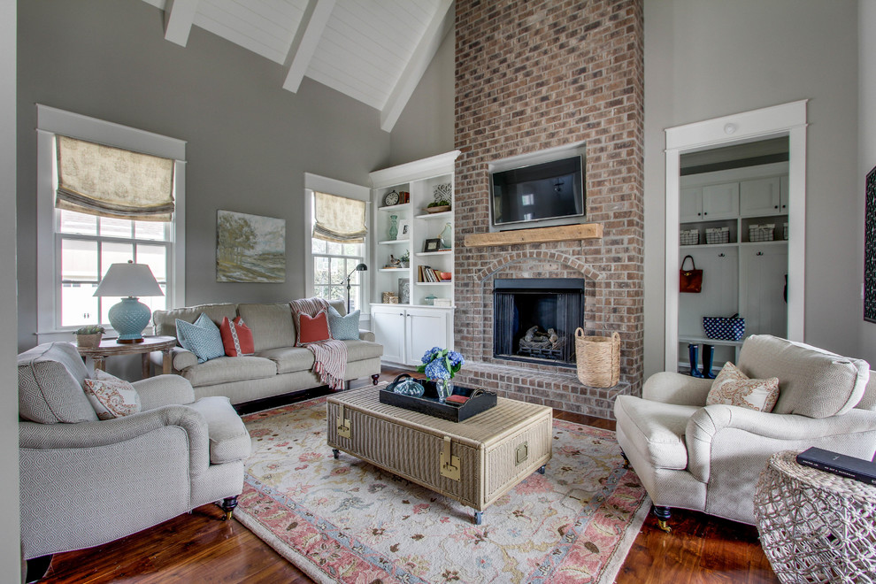 Family room - mid-sized traditional open concept medium tone wood floor family room idea in Nashville with gray walls, a standard fireplace, a brick fireplace and a wall-mounted tv
