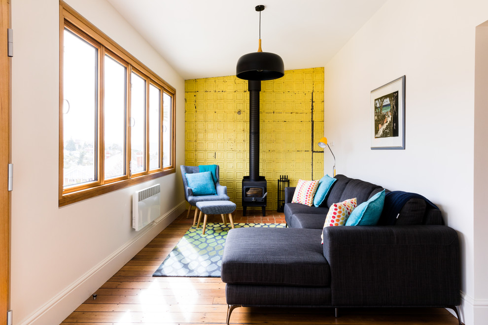 Exemple d'une salle de séjour éclectique ouverte avec un mur jaune, un sol marron, un sol en bois brun et un poêle à bois.