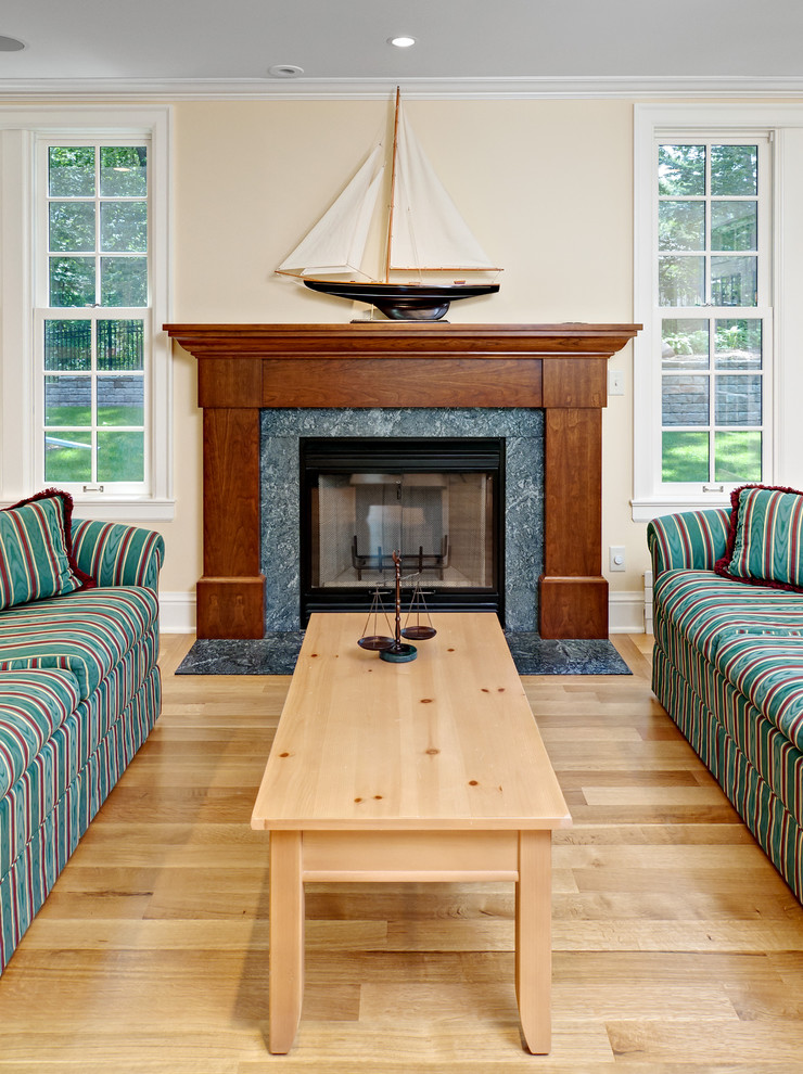 Fernseherloses Klassisches Wohnzimmer mit beiger Wandfarbe, hellem Holzboden, Kamin und Kaminumrandung aus Holz in Minneapolis
