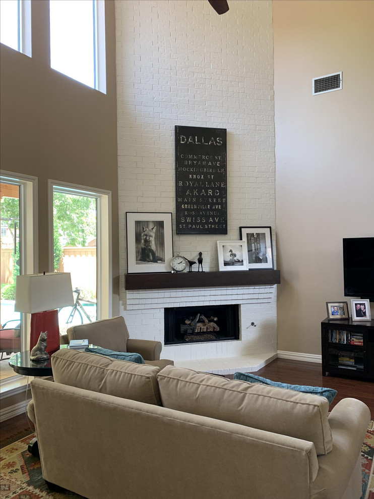Photo of a medium sized eclectic open plan games room in Other with beige walls, medium hardwood flooring, a corner fireplace, a brick fireplace surround, a freestanding tv and brown floors.