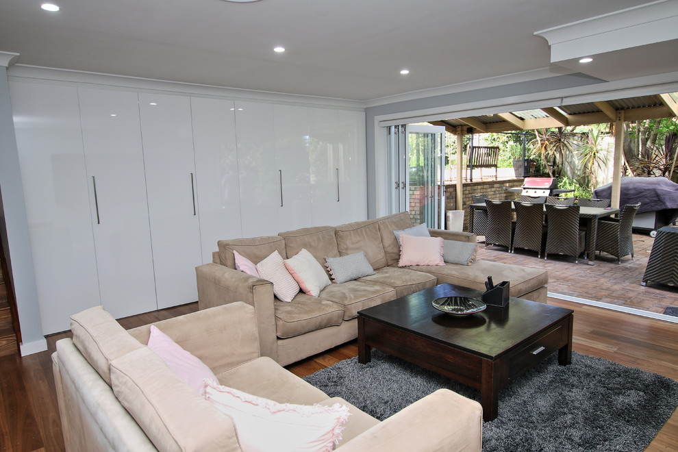 Großes, Offenes Modernes Wohnzimmer mit grauer Wandfarbe, hellem Holzboden, TV-Wand und braunem Boden in Sydney