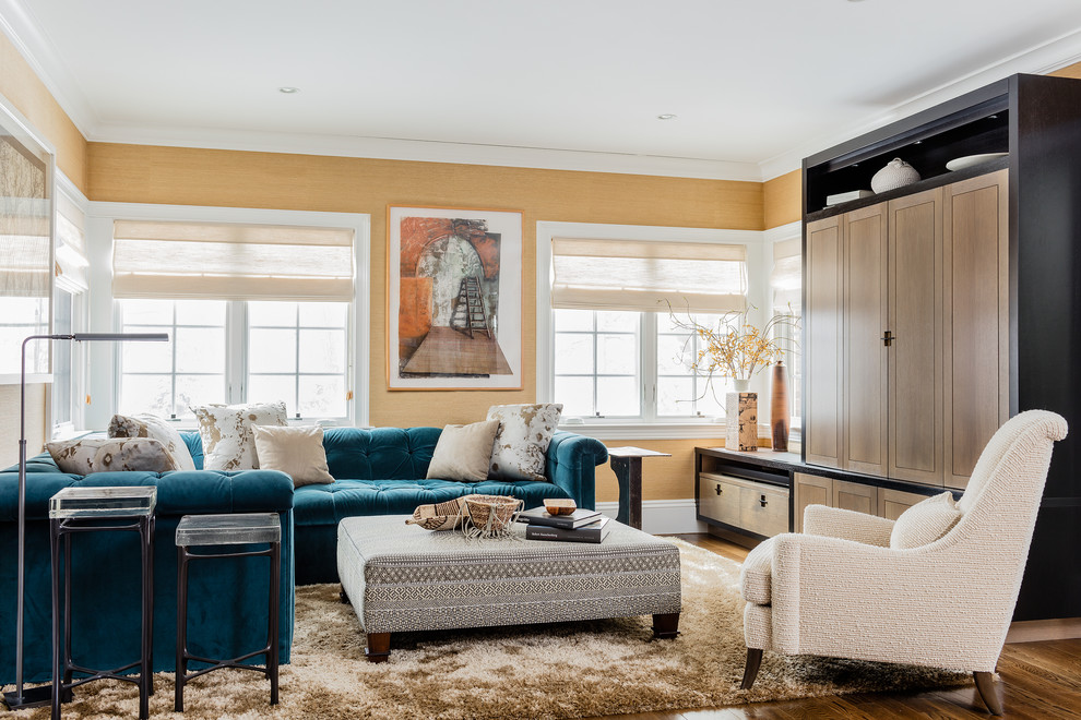 Источник вдохновения для домашнего уюта: большая открытая гостиная комната в стиле неоклассика (современная классика) с скрытым телевизором, коричневым полом, желтыми стенами, темным паркетным полом и синим диваном без камина