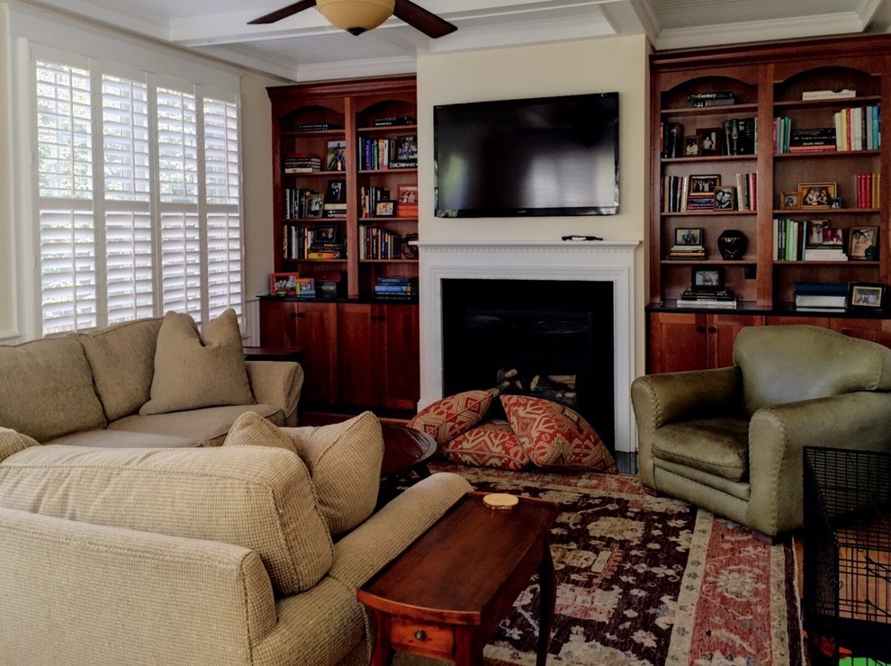 Esempio di un piccolo soggiorno classico chiuso con pareti beige, parquet chiaro, camino classico, cornice del camino in legno e TV a parete