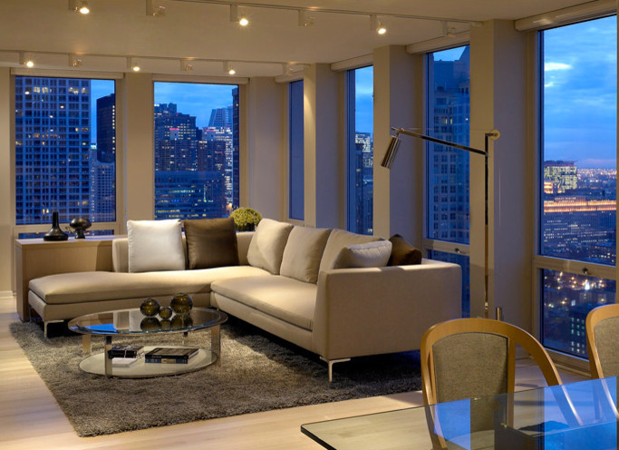 Modelo de sala de estar tipo loft moderna de tamaño medio sin chimenea y televisor con paredes beige, suelo de madera clara y suelo beige