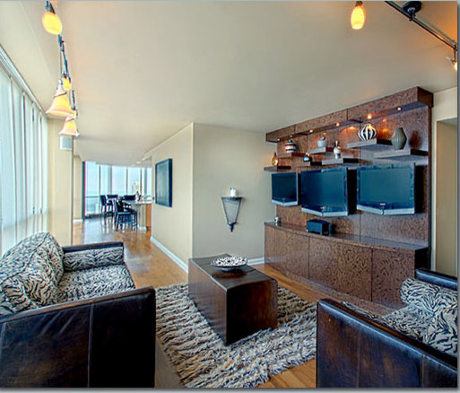Diseño de sala de estar abierta actual grande sin televisor con paredes beige y suelo de madera en tonos medios