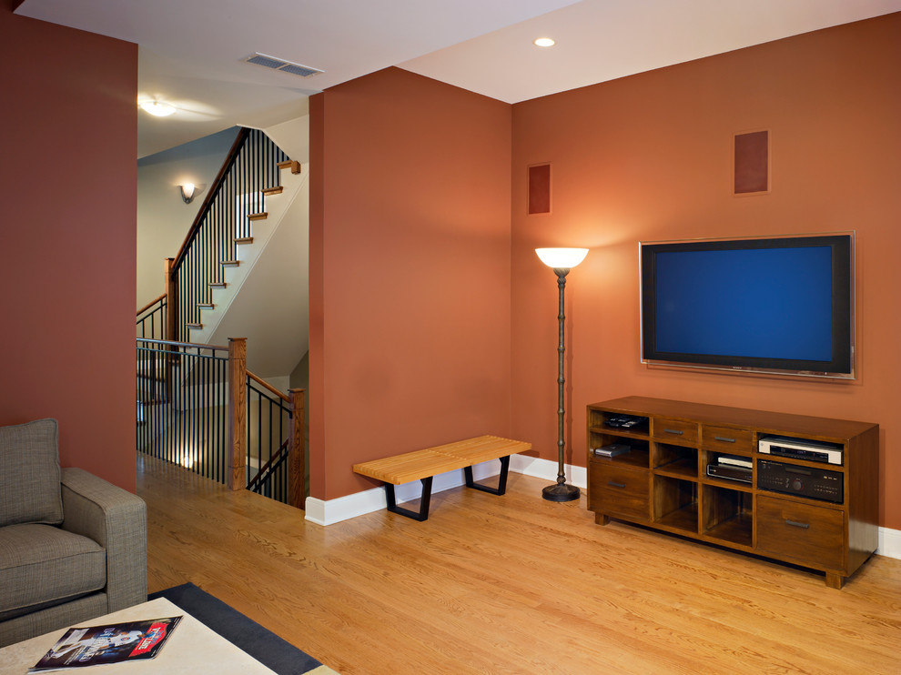 Immagine di un soggiorno design di medie dimensioni e aperto con pareti arancioni, pavimento in legno massello medio e TV a parete