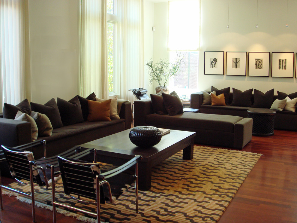 Modelo de sala de estar abierta contemporánea extra grande con paredes blancas, suelo de madera oscura y televisor colgado en la pared