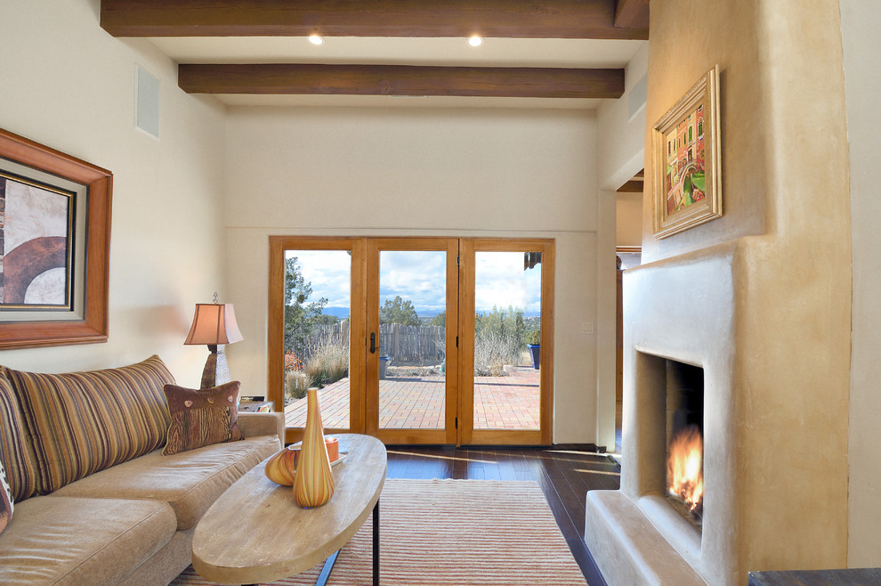 Diseño de sala de estar de estilo americano sin televisor con paredes beige, suelo de madera oscura, todas las chimeneas, marco de chimenea de yeso y suelo marrón
