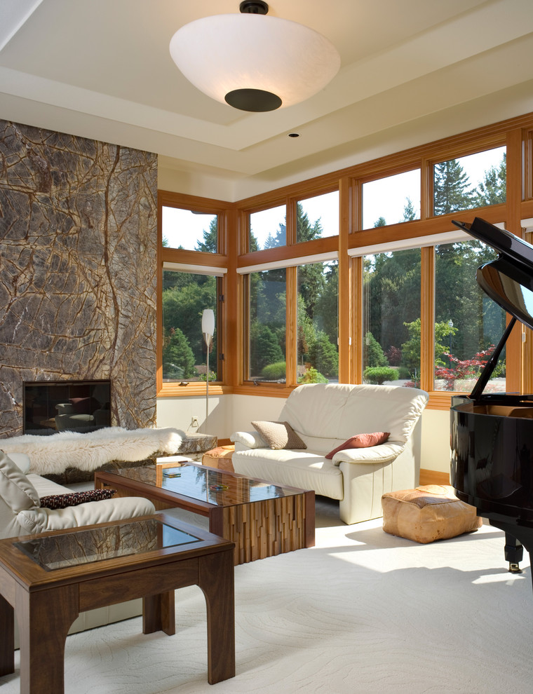 Cette photo montre une salle de séjour tendance avec une salle de musique, un mur beige, moquette, une cheminée standard et un manteau de cheminée en pierre.