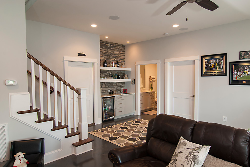 Imagen de sala de estar con barra de bar abierta clásica renovada de tamaño medio con paredes grises, suelo de cemento, televisor colgado en la pared y suelo gris