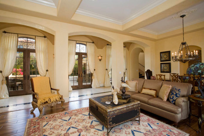 Diseño de sala de estar cerrada mediterránea grande sin chimenea y televisor con paredes beige y suelo de madera en tonos medios