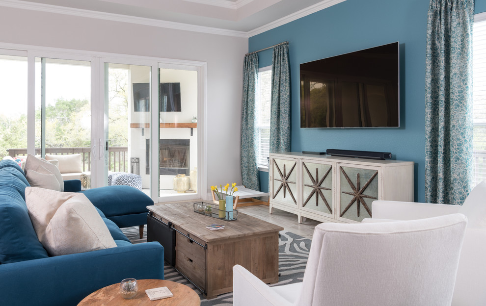 Идея дизайна: гостиная комната в морском стиле с синими стенами, телевизором на стене, серым полом и синим диваном