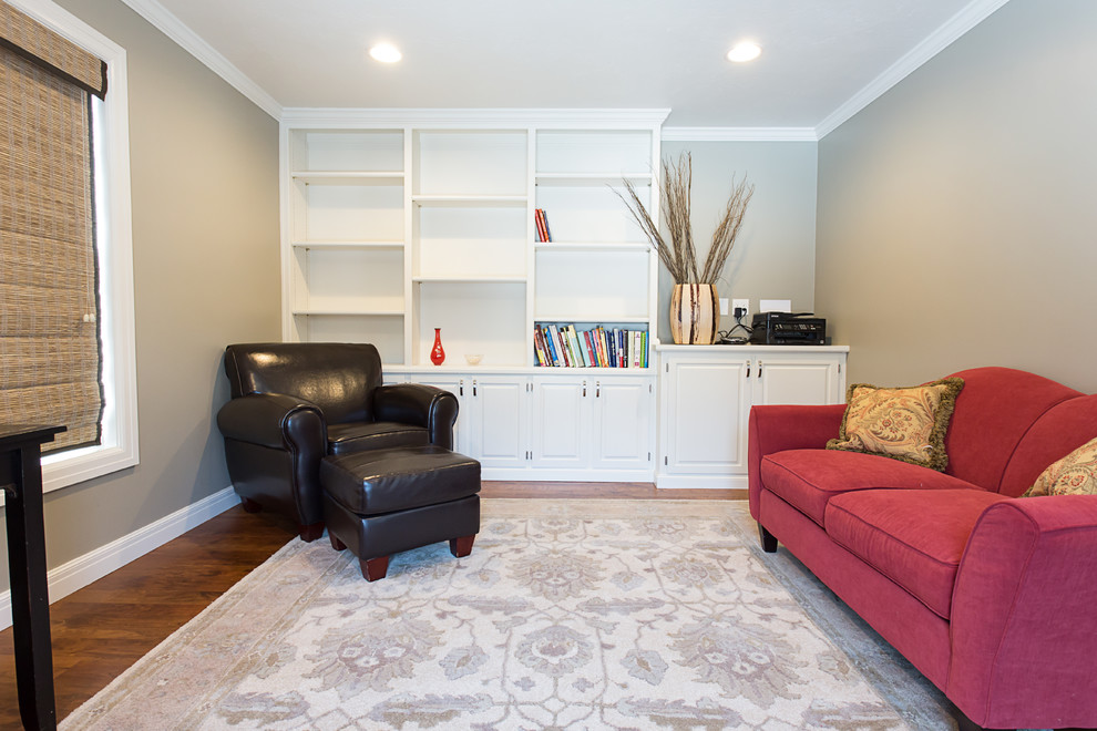 Foto de sala de estar con biblioteca cerrada tradicional renovada de tamaño medio sin chimenea y televisor con paredes grises y suelo de madera en tonos medios