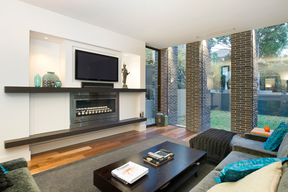 Inspiration for a contemporary games room in Melbourne with white walls, medium hardwood flooring, a ribbon fireplace, a metal fireplace surround and a wall mounted tv.