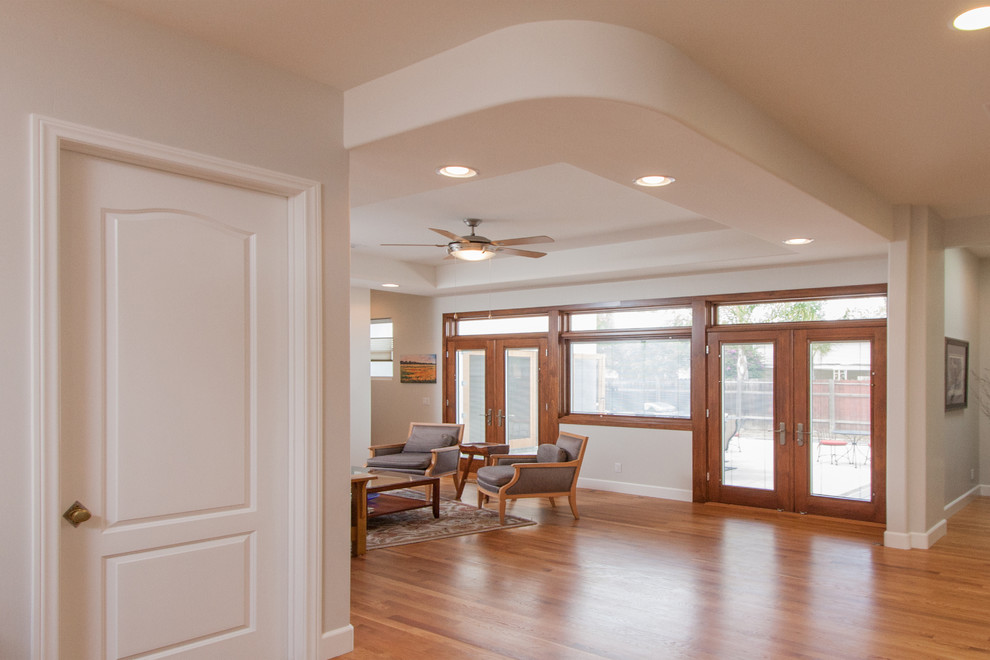Offenes Klassisches Wohnzimmer ohne Kamin mit weißer Wandfarbe, hellem Holzboden und TV-Wand in San Diego