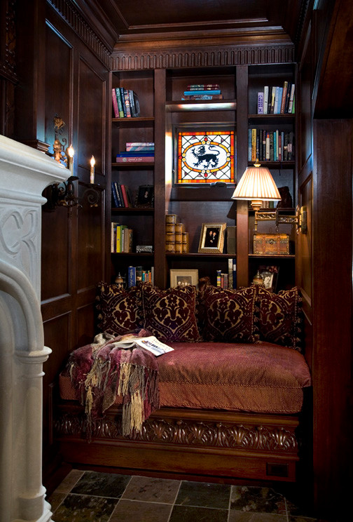 Foto di un piccolo soggiorno chiuso con libreria, pareti marroni, pavimento in ardesia, camino classico, cornice del camino in pietra e nessuna TV