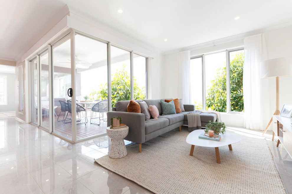 Imagen de sala de estar abierta extra grande con paredes blancas, suelo de baldosas de cerámica, televisor independiente y suelo blanco
