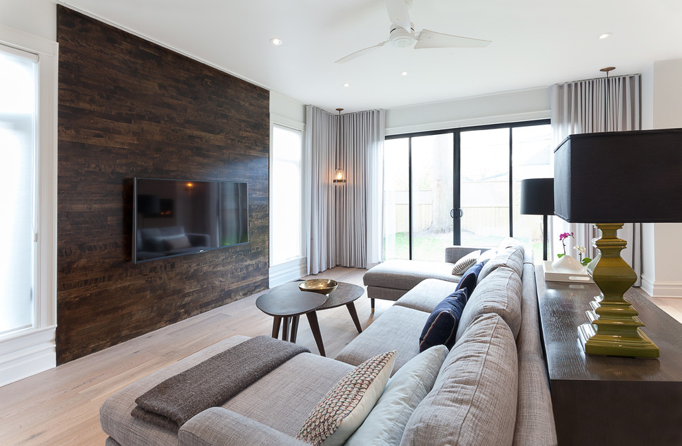 Modelo de sala de estar abierta contemporánea grande sin chimenea con paredes blancas, suelo de madera clara, televisor colgado en la pared y suelo beige
