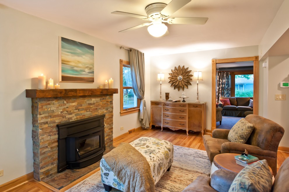 Foto de sala de estar abierta clásica de tamaño medio con paredes grises, suelo de madera en tonos medios, todas las chimeneas y marco de chimenea de piedra