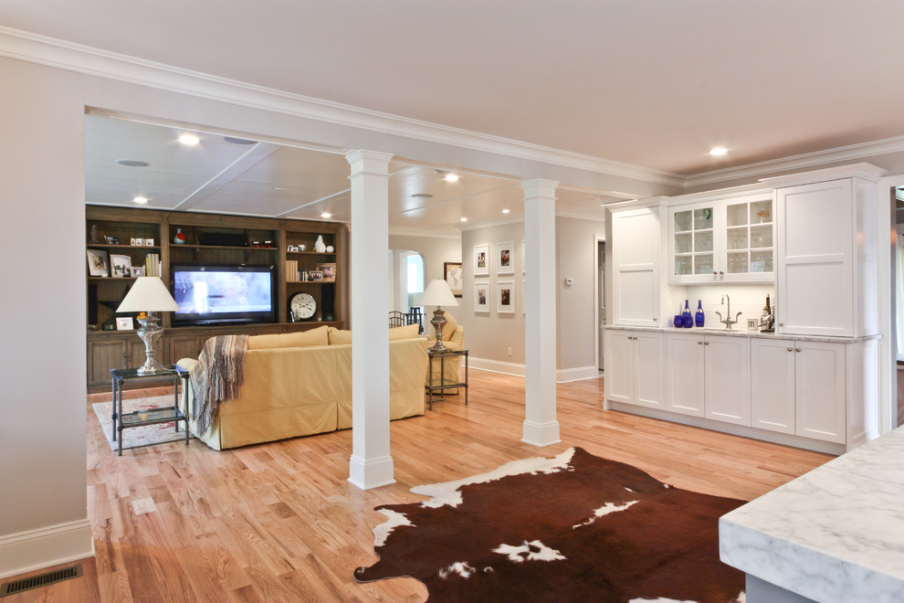 Foto de sala de estar abierta clásica con paredes beige, suelo de madera clara y pared multimedia