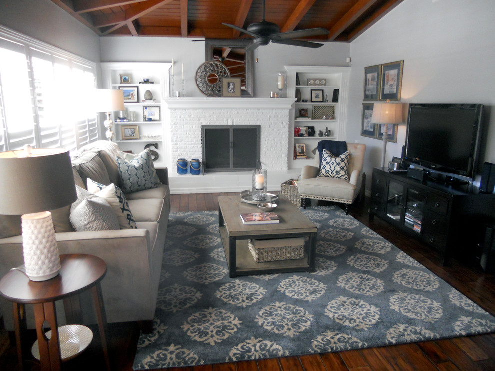 Foto de sala de estar abierta tradicional renovada de tamaño medio con paredes grises, suelo de madera en tonos medios, todas las chimeneas, marco de chimenea de ladrillo y televisor independiente