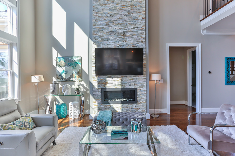 Mittelgroßes, Offenes Modernes Wohnzimmer mit grauer Wandfarbe, braunem Holzboden, Gaskamin, Kaminumrandung aus Stein und TV-Wand in Raleigh