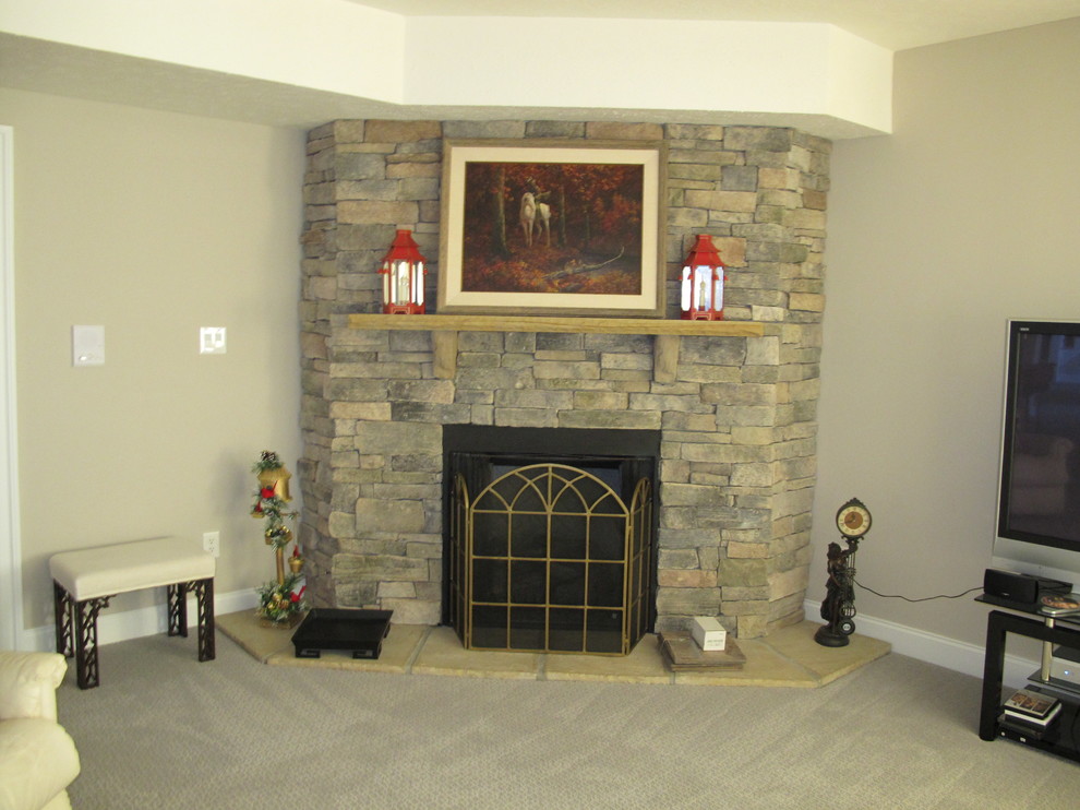 Aménagement d'une salle de séjour classique de taille moyenne et fermée avec un mur gris, moquette, une cheminée d'angle, un manteau de cheminée en pierre et un téléviseur indépendant.
