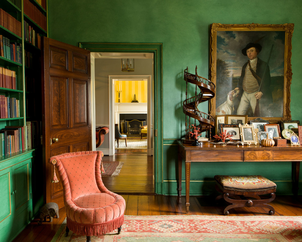 На фото: гостиная комната в классическом стиле с зелеными стенами и с книжными шкафами и полками с