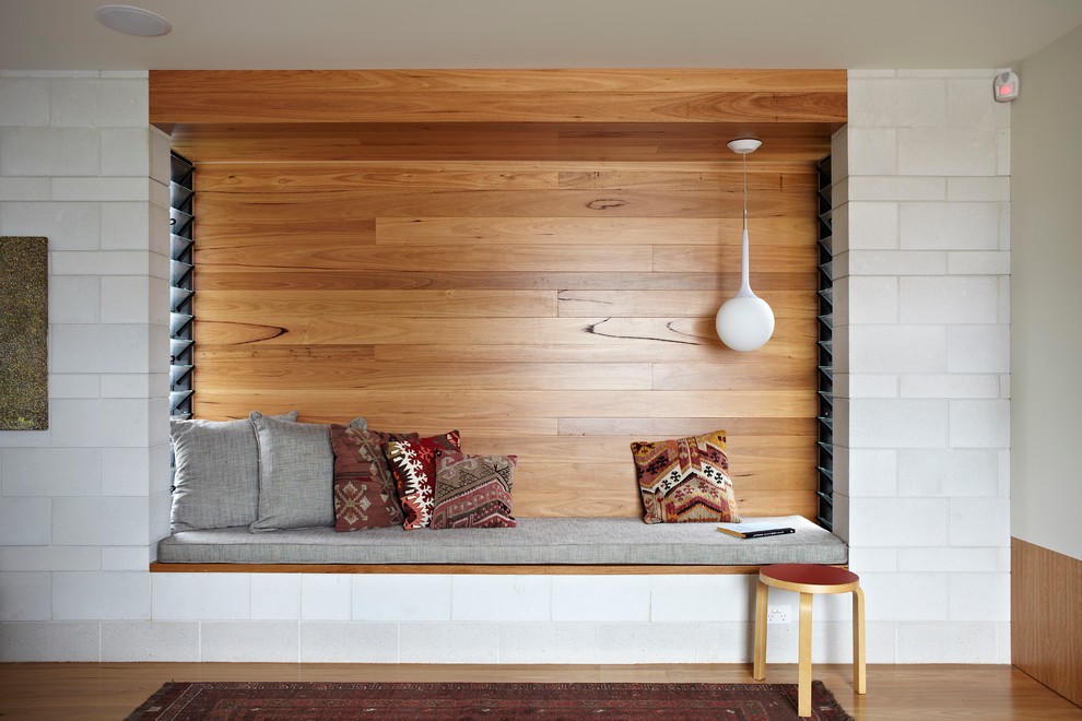 Cette image montre une salle de séjour design avec un mur blanc et un sol en bois brun.