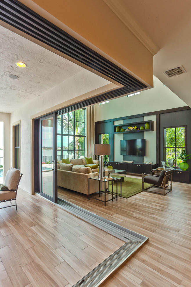 Идея дизайна: большая открытая гостиная комната в современном стиле с бежевыми стенами, полом из бамбука и телевизором на стене без камина