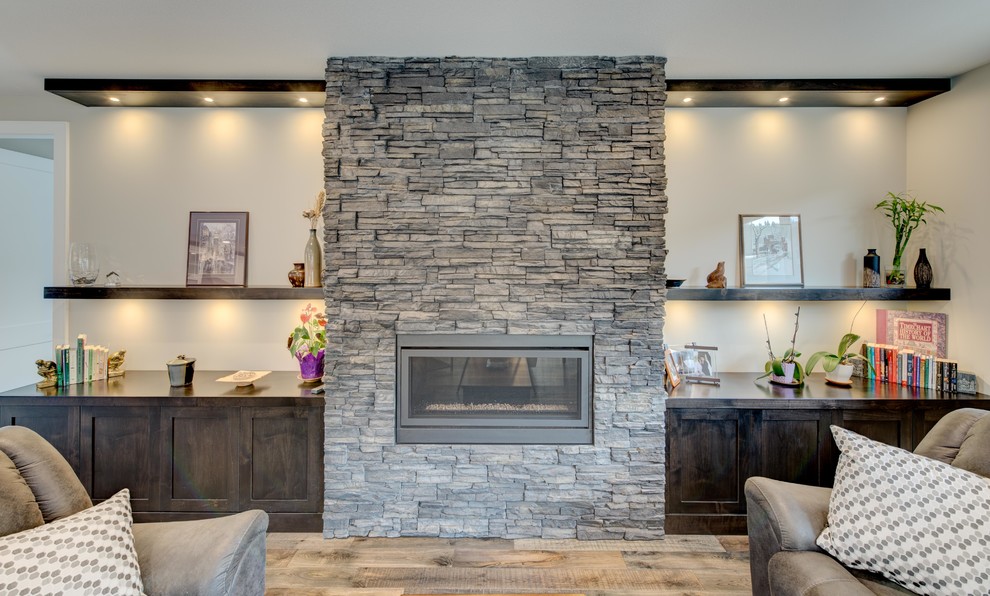 Photo of a medium sized traditional open plan games room in Vancouver with grey walls, medium hardwood flooring, a ribbon fireplace, a stone fireplace surround and no tv.