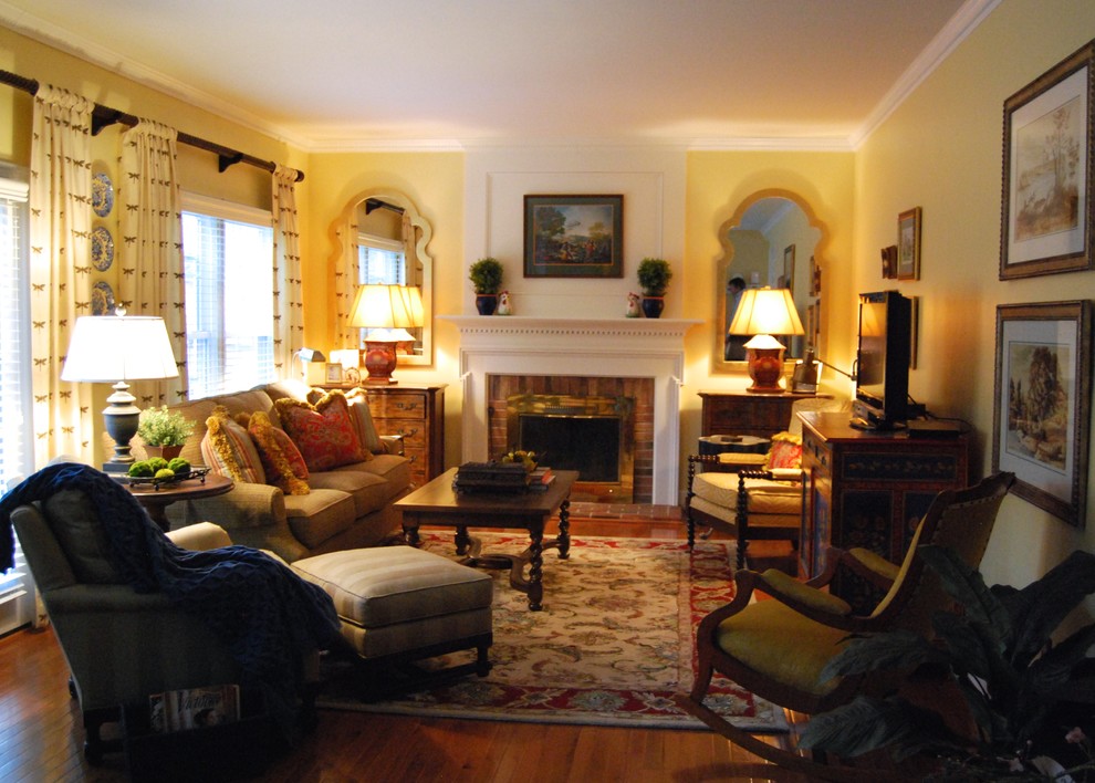 Стильный дизайн: гостиная комната среднего размера в классическом стиле с желтыми стенами, темным паркетным полом, стандартным камином, фасадом камина из дерева и отдельно стоящим телевизором - последний тренд