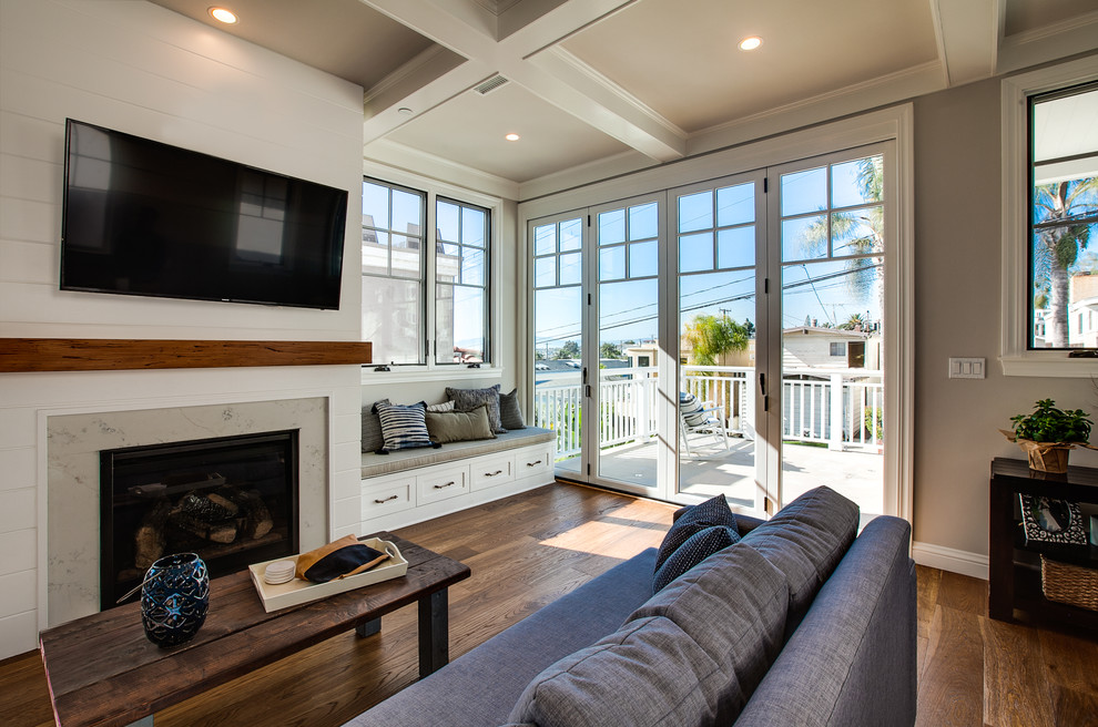 Design ideas for a coastal open plan games room in San Diego with grey walls, medium hardwood flooring, a standard fireplace, a stone fireplace surround, a wall mounted tv and brown floors.
