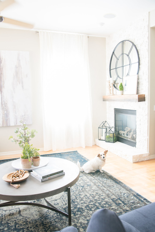 Modelo de sala de estar abierta romántica de tamaño medio con paredes grises, suelo de madera clara, todas las chimeneas, marco de chimenea de piedra, televisor colgado en la pared, suelo amarillo y alfombra
