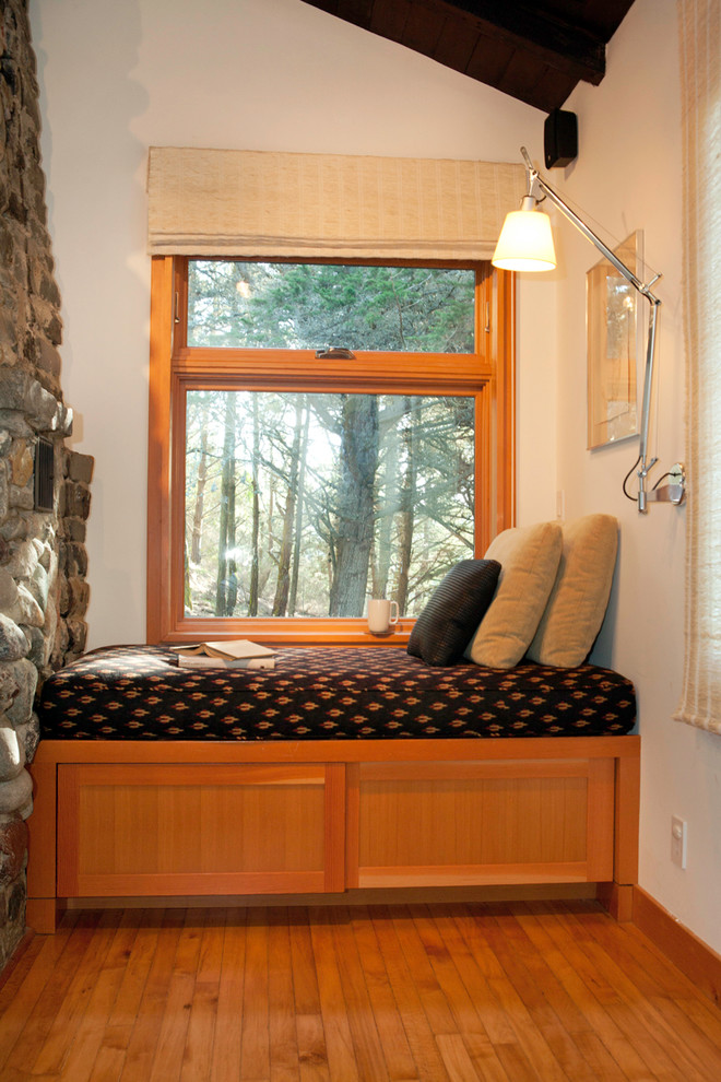 Inspiration pour une petite salle de séjour design ouverte avec un sol en bois brun, un manteau de cheminée en pierre, un mur blanc, un poêle à bois et aucun téléviseur.