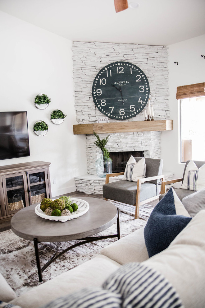 Mid-sized beach style open concept laminate floor and gray floor family room photo in Phoenix with white walls, a corner fireplace, a stone fireplace and a wall-mounted tv