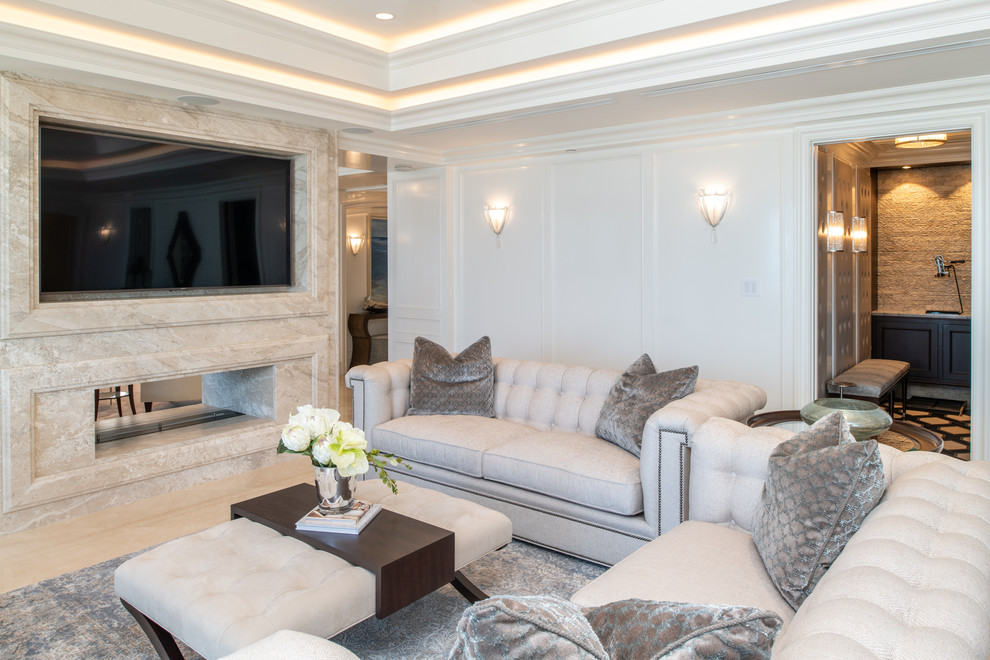 Diseño de sala de estar marinera con paredes blancas, chimenea de doble cara, marco de chimenea de piedra, pared multimedia y suelo beige