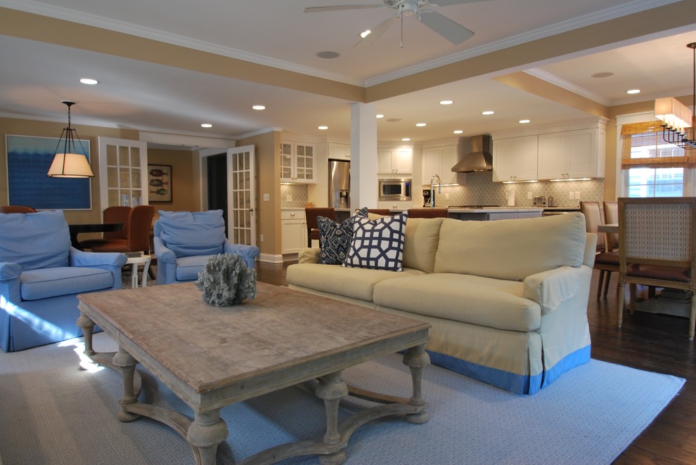 Diseño de sala de estar abierta clásica renovada grande con paredes beige, suelo de madera oscura, televisor colgado en la pared y suelo marrón