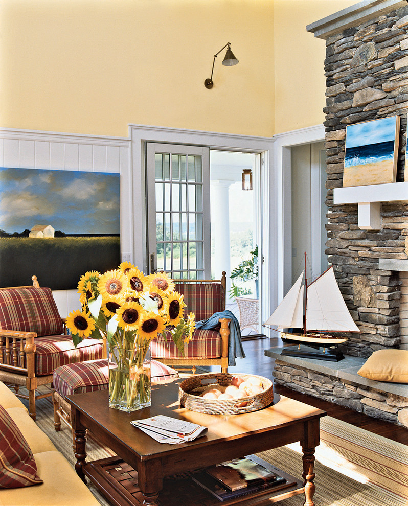Diseño de sala de estar costera con marco de chimenea de piedra y paredes amarillas