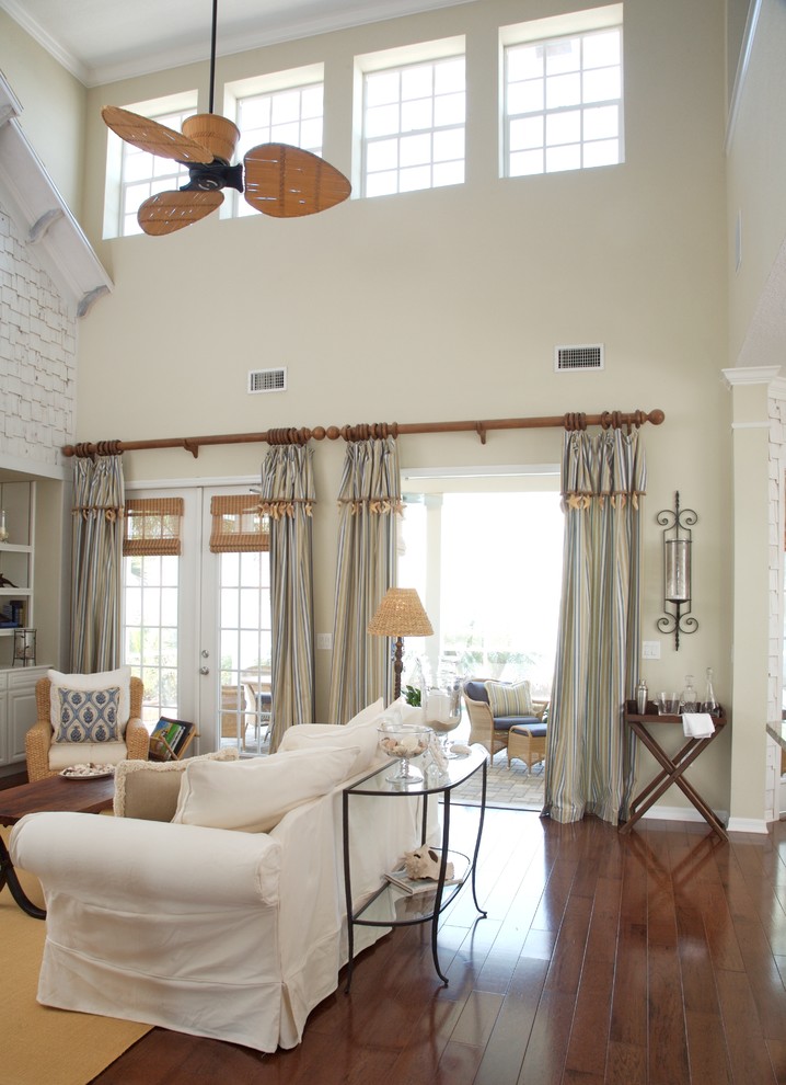 Mittelgroßes Maritimes Wohnzimmer im Loft-Stil mit beiger Wandfarbe, dunklem Holzboden, Kamin, Kaminumrandung aus Stein, TV-Wand und braunem Boden in Tampa