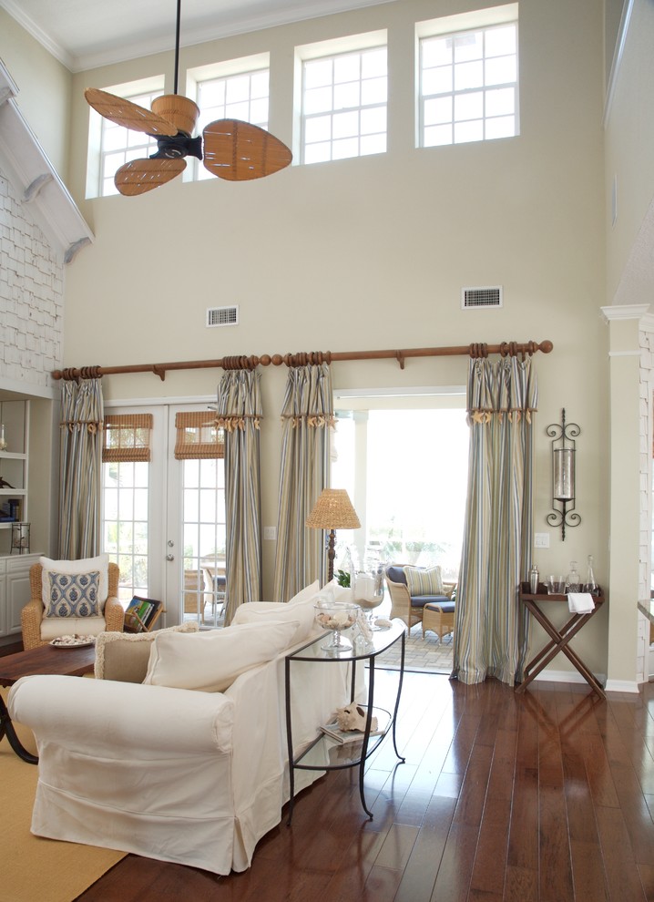 Example of a mid-sized beach style loft-style dark wood floor and brown floor family room design in Tampa with beige walls, a standard fireplace, a stone fireplace and a wall-mounted tv