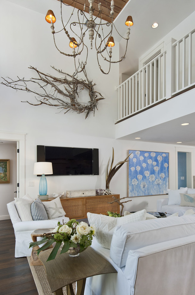 Modelo de sala de estar abierta costera con paredes blancas, suelo de madera oscura y televisor colgado en la pared