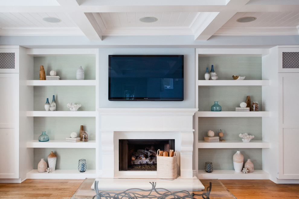Diseño de sala de estar abierta costera grande con paredes azules, suelo de madera clara, todas las chimeneas, marco de chimenea de yeso y televisor colgado en la pared